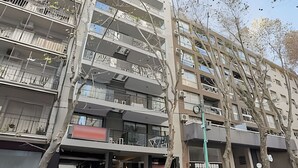 Un immeuble à plusieurs étages doté de balcons, d’un espace de stationnement et d’arbres.