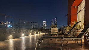 Une terrasse sur le toit offrant une vue sur les bâtiments de la ville la nuit.