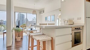 Une cuisine moderne dotée d’un îlot central, d’un four encastré et de luminaires suspendus.