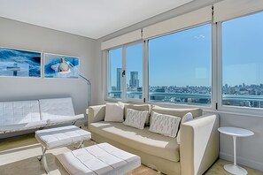 Ein modernes Wohnzimmer mit großem Fenster, einer Couch, einem Couchtisch und einem Beistelltisch.