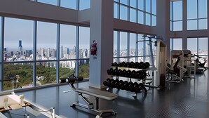 A gym with large windows, exercise equipment, and a city view. - Luxury 2BR Apartment with Pool, Gym & Spa (Buenos Aires)
