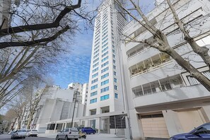 A modern multi-story building with a flat facade, large windows, and a garage entrance.