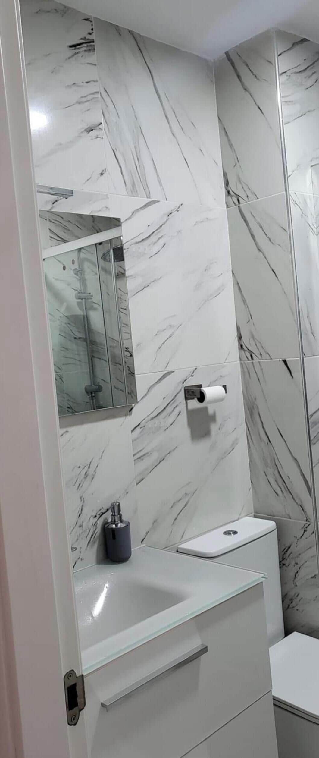 Une salle de bain avec un mur en marbre, des toilettes, un lavabo et un miroir.