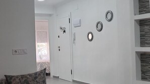 A modern living room with a sofa, a door with a mirror, and a wall with decorative plates. - Sunny Gandia Apartment With 2 Bedrooms (Gandia)