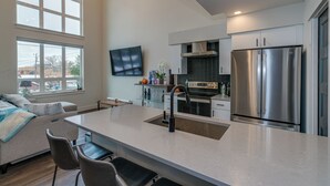 Una cocina moderna con una isla central, electrodomésticos de acero inoxidable y un televisor de pantalla plana montado en la pared.