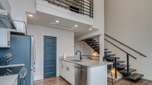 Una cocina moderna con lavavajillas incorporado, una puerta azul y una escalera que conduce a un nivel superior.