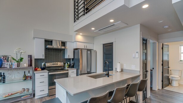 Una cocina moderna con una isla central, electrodomésticos de acero inoxidable y una zona de bar con taburetes.