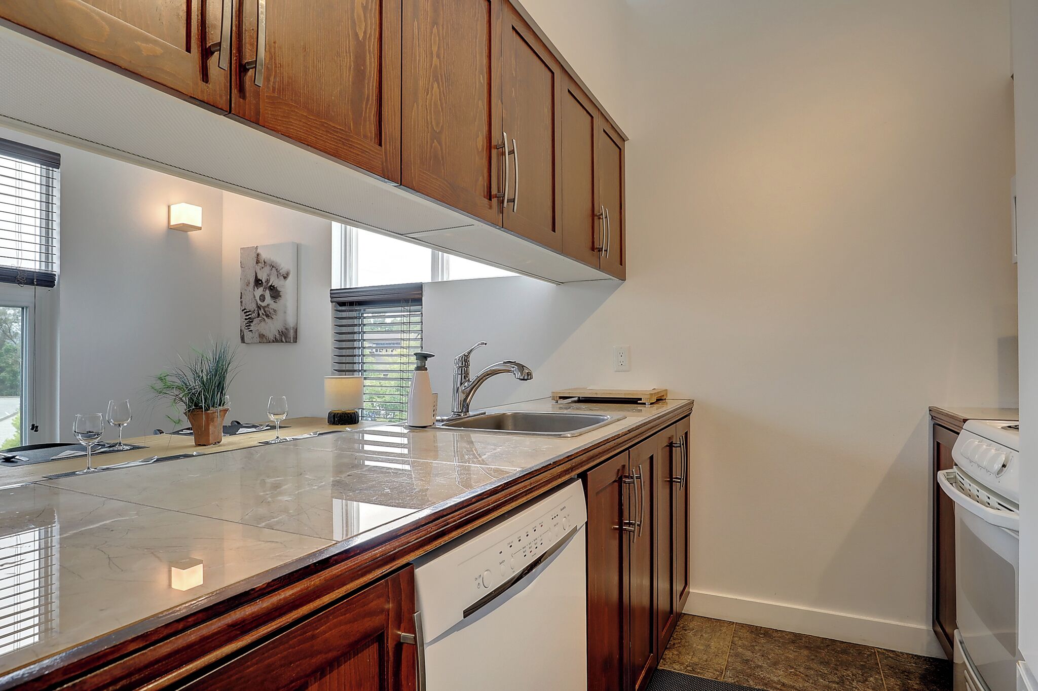 A kitchen with wooden cabinets, a marble countertop, a dishwasher, and a sink.