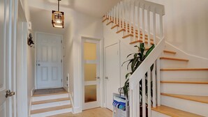 A staircase with wooden steps and white railings, a door with frosted glass panels, and a hanging light fixture. - Condotel (Magog)