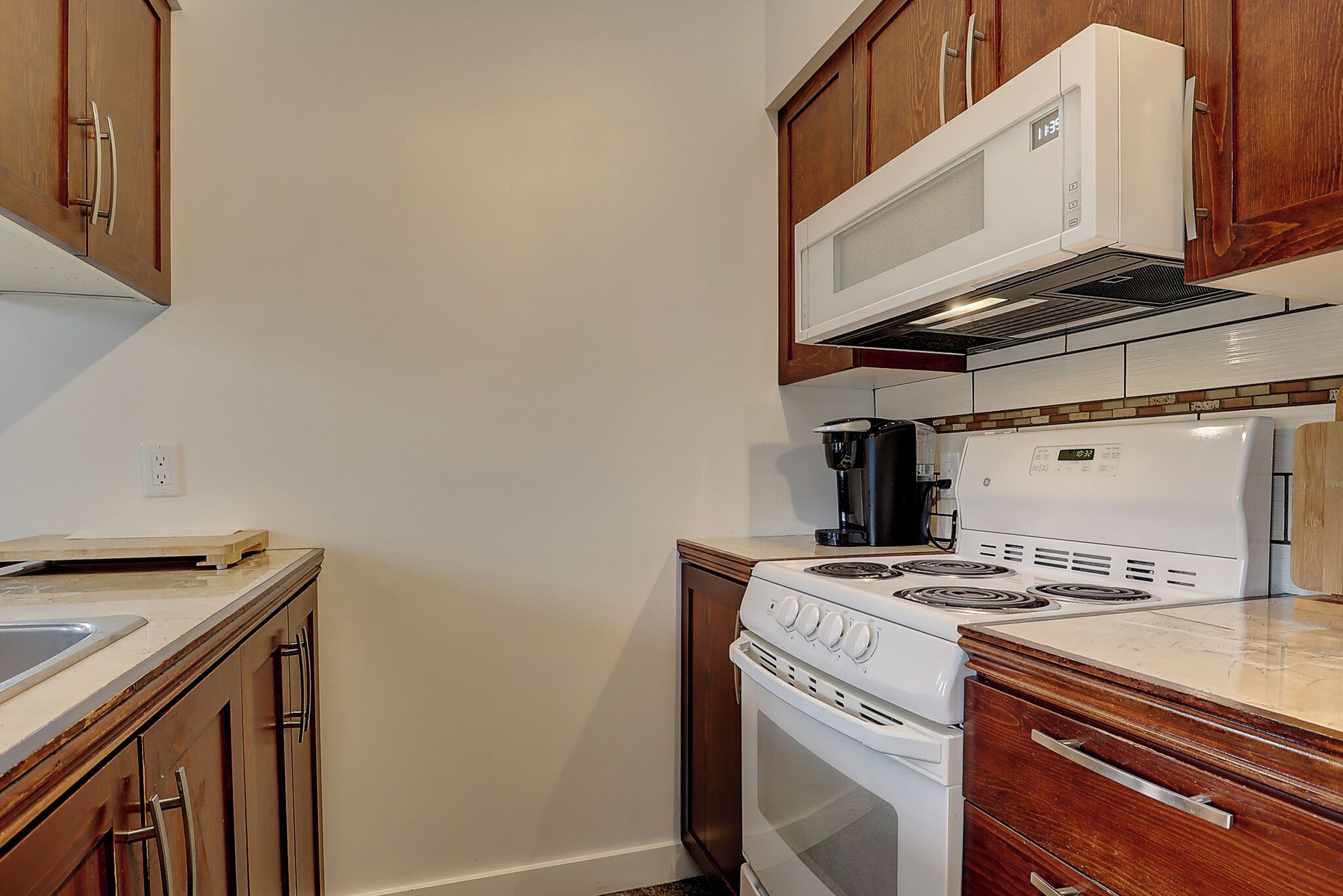 A kitchen with wooden cabinets, a white stove, and a microwave.