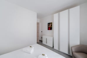 A modern hotel room with a bed, a chest of drawers, a seating area, and a framed picture on the wall. - La Dimora di Nobile II by Rentbeat (Carovigno)