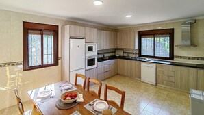 A modern kitchen with a dining area, featuring a refrigerator, oven, microwave, and dishwasher. - Cómpeta Rural - Casa La Niña by Ruralidays (Málaga)