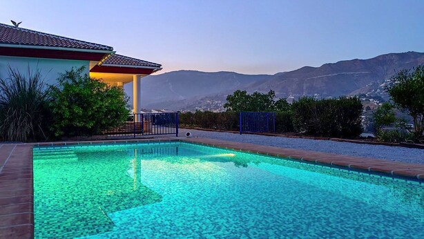 A swimming pool with a tiled deck, surrounded by greenery and a view of mountains. - Cómpeta Rural - Casa La Niña by Ruralidays (Málaga)