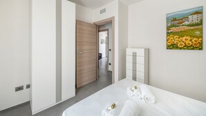A hotel room with a bed, towels, a painting, and a wardrobe. - La Dimora di Nobile I by Rentbeat (Carovigno)