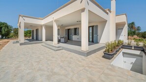 A modern house with a covered patio, a chimney, and a garden area. - La Dimora di Nobile I by Rentbeat (Carovigno)
