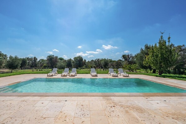 A rectangular swimming pool with clear blue water, surrounded by a tiled deck.