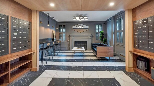 Eine moderne Lobby mit Schachbrettmuster-Boden, Kamin und einer Sitzecke mit Couchtisch.