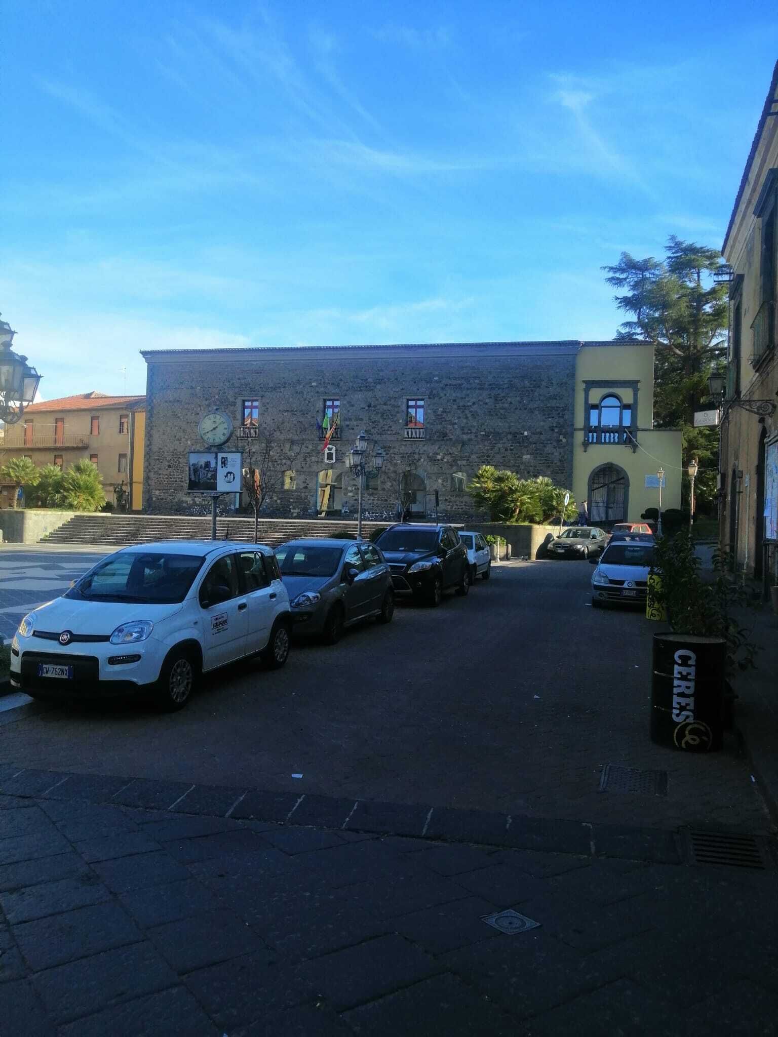 Une rue bordée de voitures garées et un immeuble avec une horloge.