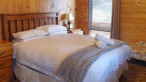 Une chambre aux murs lambrés, avec un lit, une table de chevet, une lampe et un canapé à motifs floraux.