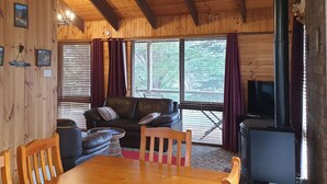 L’intérieur d’un chalet chaleureux, avec une table à manger en bois, un canapé en cuir et un téléviseur.
