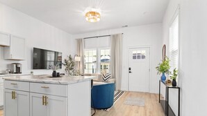 Una cocina moderna con armarios blancos, encimera de mármol y una silla azul.