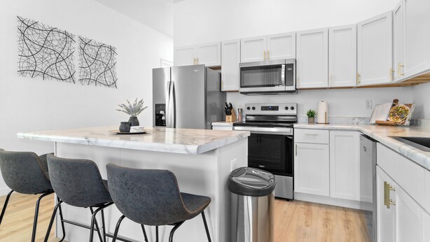 Una cocina moderna con armarios blancos, electrodomésticos de acero inoxidable y encimera de mármol.