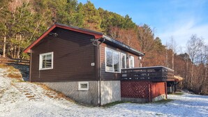 A two-story wooden cabin with a red roof, numbered 241, situated in a snowy forest.