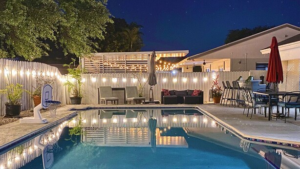 A swimming pool with a deck area, outdoor furniture, and string lights. - Family Favorite-Heated Pool/2 Kings/Everglades (Homestead)