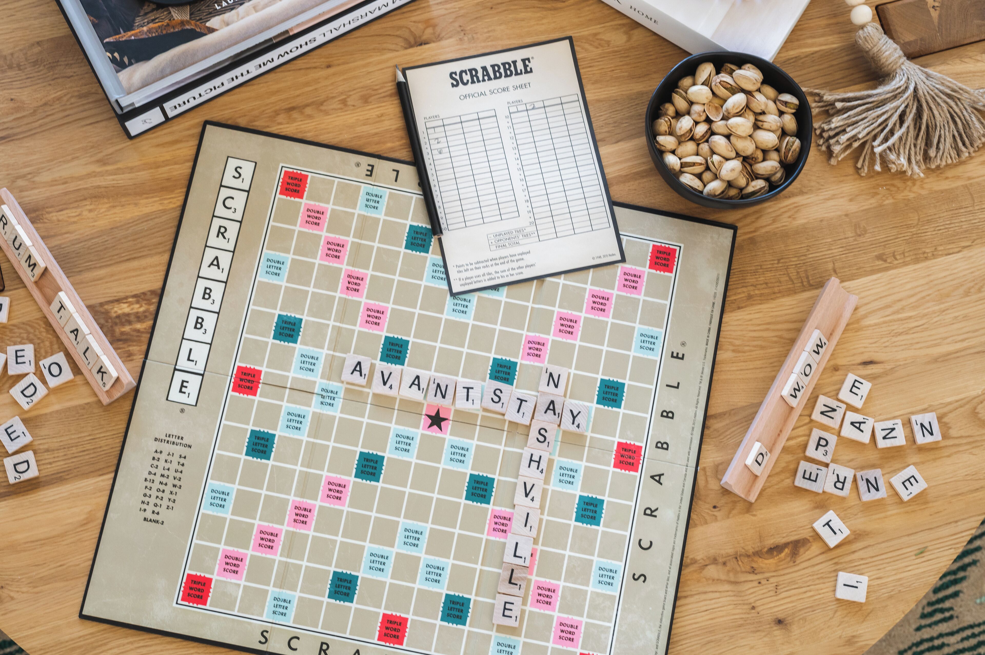 Een Scrabble spelbord met lettertegels en een scoreblad op een houten tafel.