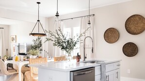 Een moderne keuken met een centraal eiland, witte keukenkastjes en een RVS vaatwasser.