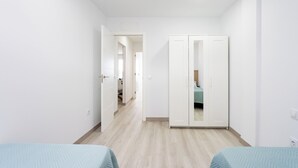 Een kamer met twee bedden, een kledingkast en een spiegel.