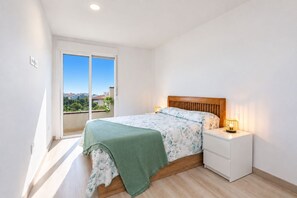 A bedroom with a bed, bedside table, and a view of the city. - Home2Book Relaxing Poolside Escape, Arona (Adeje)