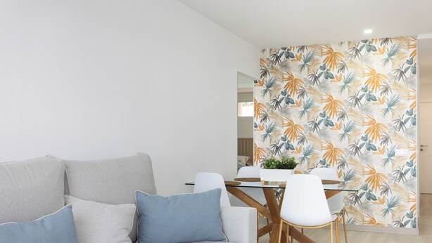 Een moderne woonkamer met een grijze bank, witte stoelen en een glazen eettafel.