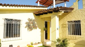 A building with a yellow facade, a tiled roof, and barred windows.