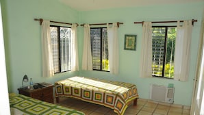 A room with two beds, a radiator, and a window with curtains.