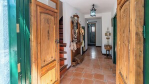 Un pasillo con puertas de madera, una escalera y suelo de baldosas.