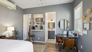 Un dormitorio moderno con cama, mesita de noche, lámpara y vistas a una zona de cocina.