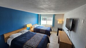 Habitación de hotel con dos camas, televisión y escritorio.
