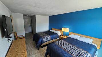 Una habitación de hotel con dos camas, televisión, escritorio y lámpara.