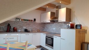 A compact kitchen with white cabinets, a built-in oven, and a coffee machine. - Excl. Apartment for the discerning, 75 sqm, attic, 2 pers. (Heeßen)