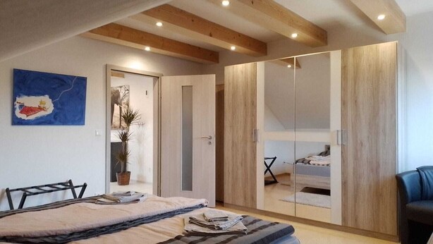 A bedroom with a bed, a wardrobe, a desk, and a chair. - Excl. Apartment for the discerning, 75 sqm, attic, 2 pers. (Heeßen)