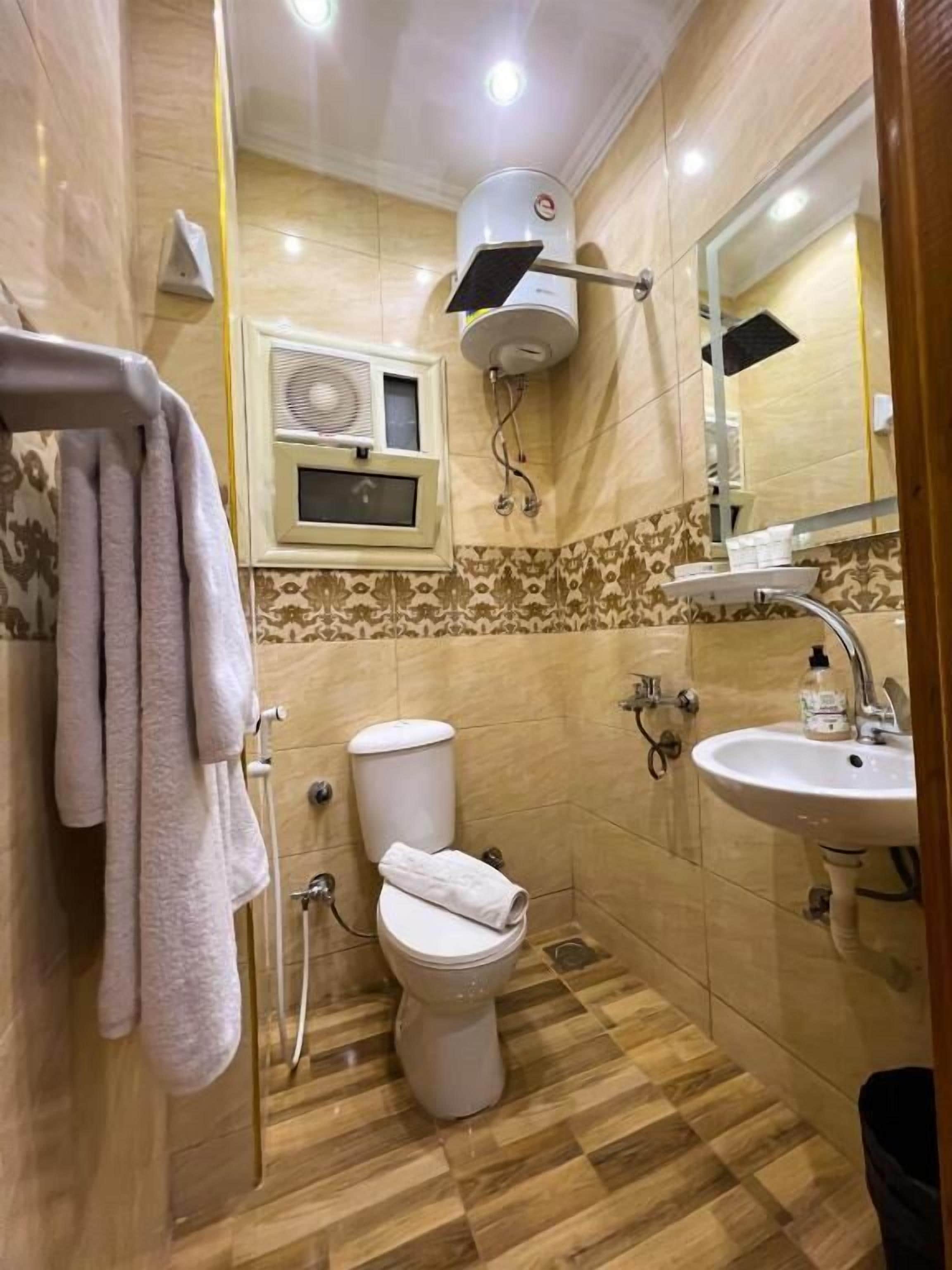Un bagno con il water, lavandino, porta asciugamani e specchio.