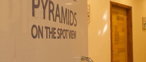Una pared con el texto 'PYRAMIDS ON THE SPOT VIEW', una puerta de madera y una barandilla de metal.