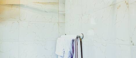 Une douche avec un pommeau de douche amovible et un porte-serviettes avec des serviettes.