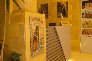 Zona de recepción con una escalera, un mostrador de recepción y carteles informativos en las paredes.