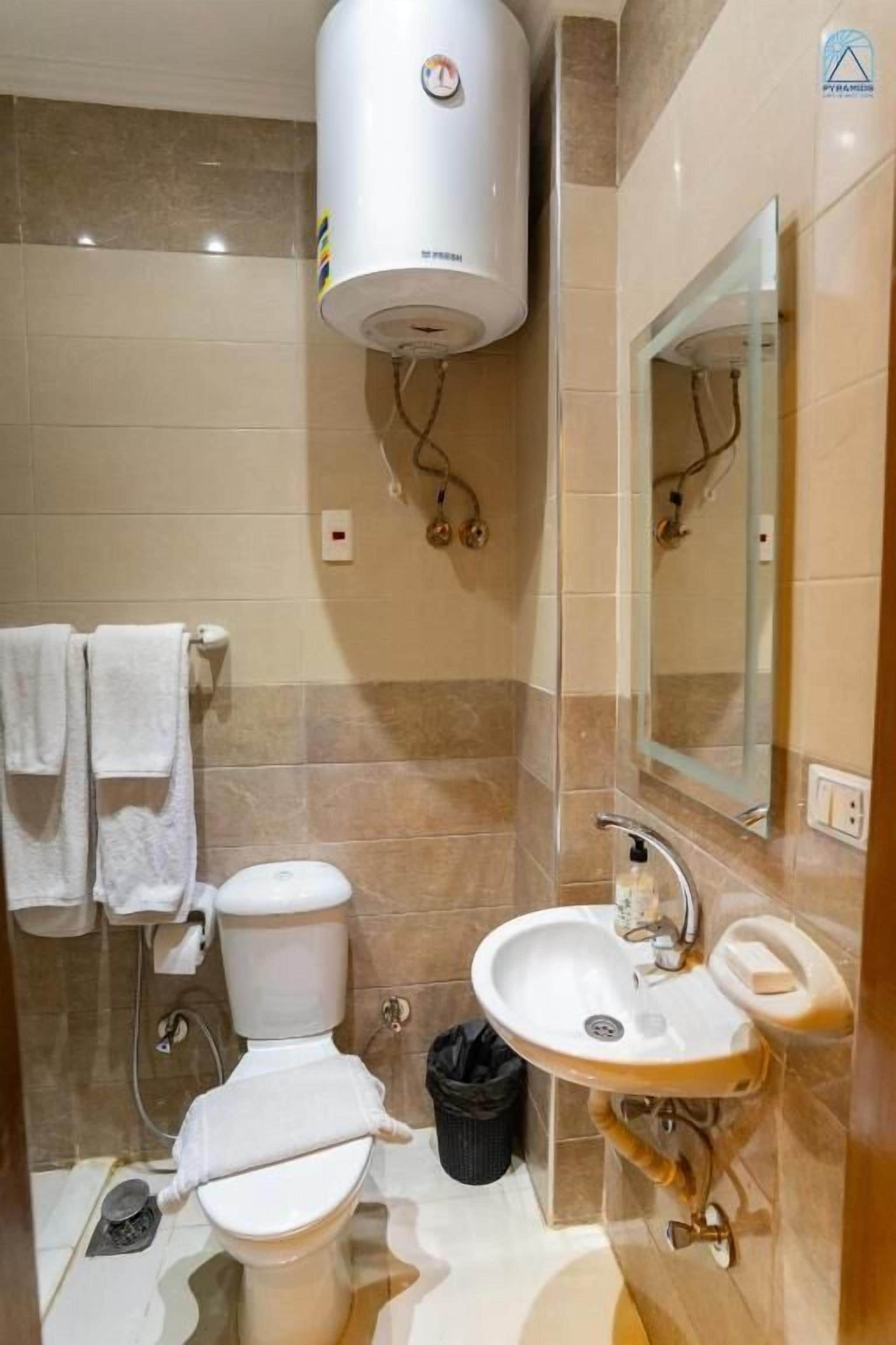 Un bagno con il water, lavandino, specchio, porta asciugamani e scaldabagno.