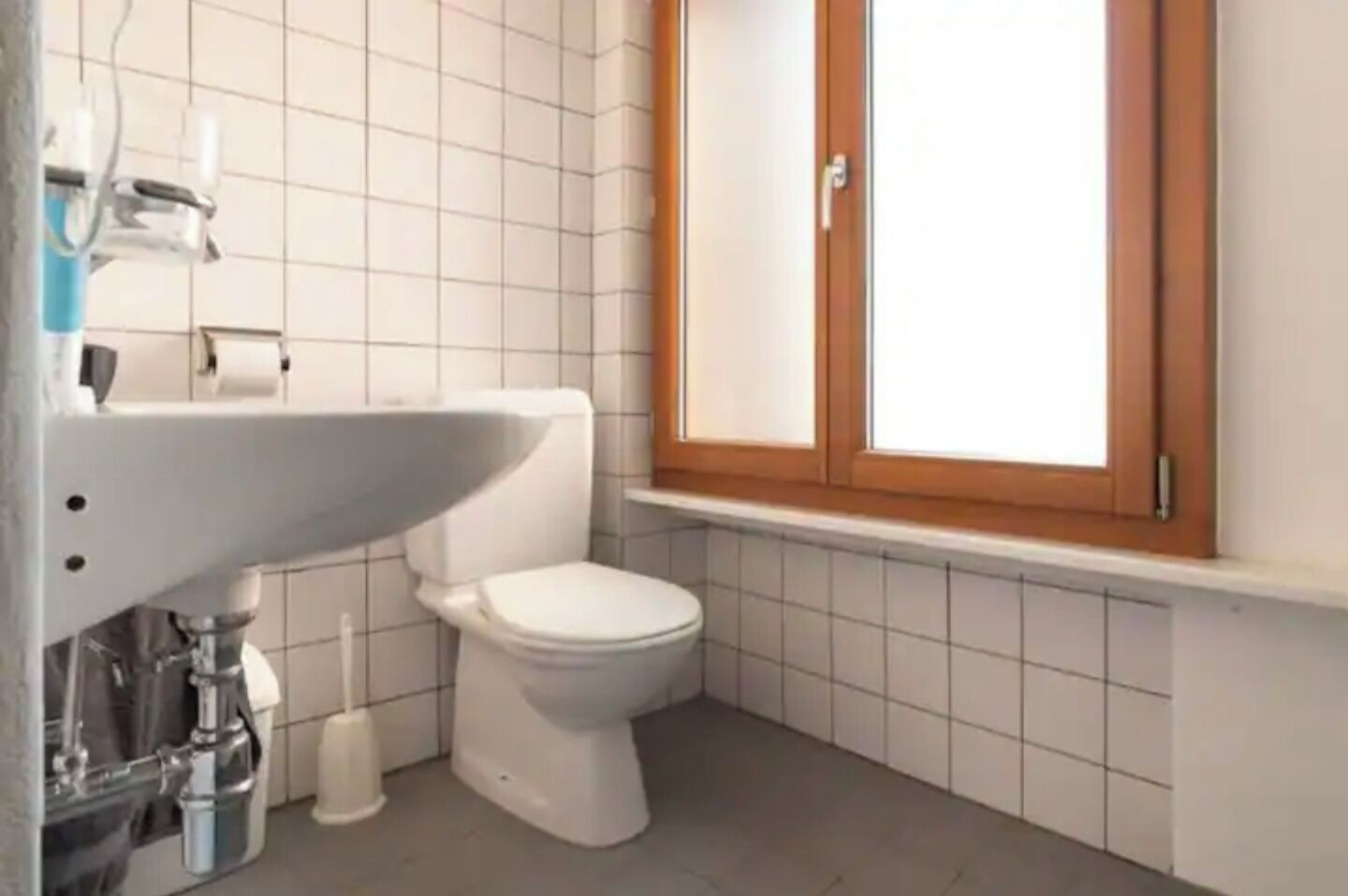 A small bathroom with a white toilet, a sink, and a cabinet above the toilet.