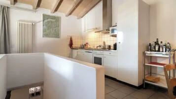 Une cuisine moderne avec des meubles blancs, un four à micro-ondes et un meuble à bouteilles.