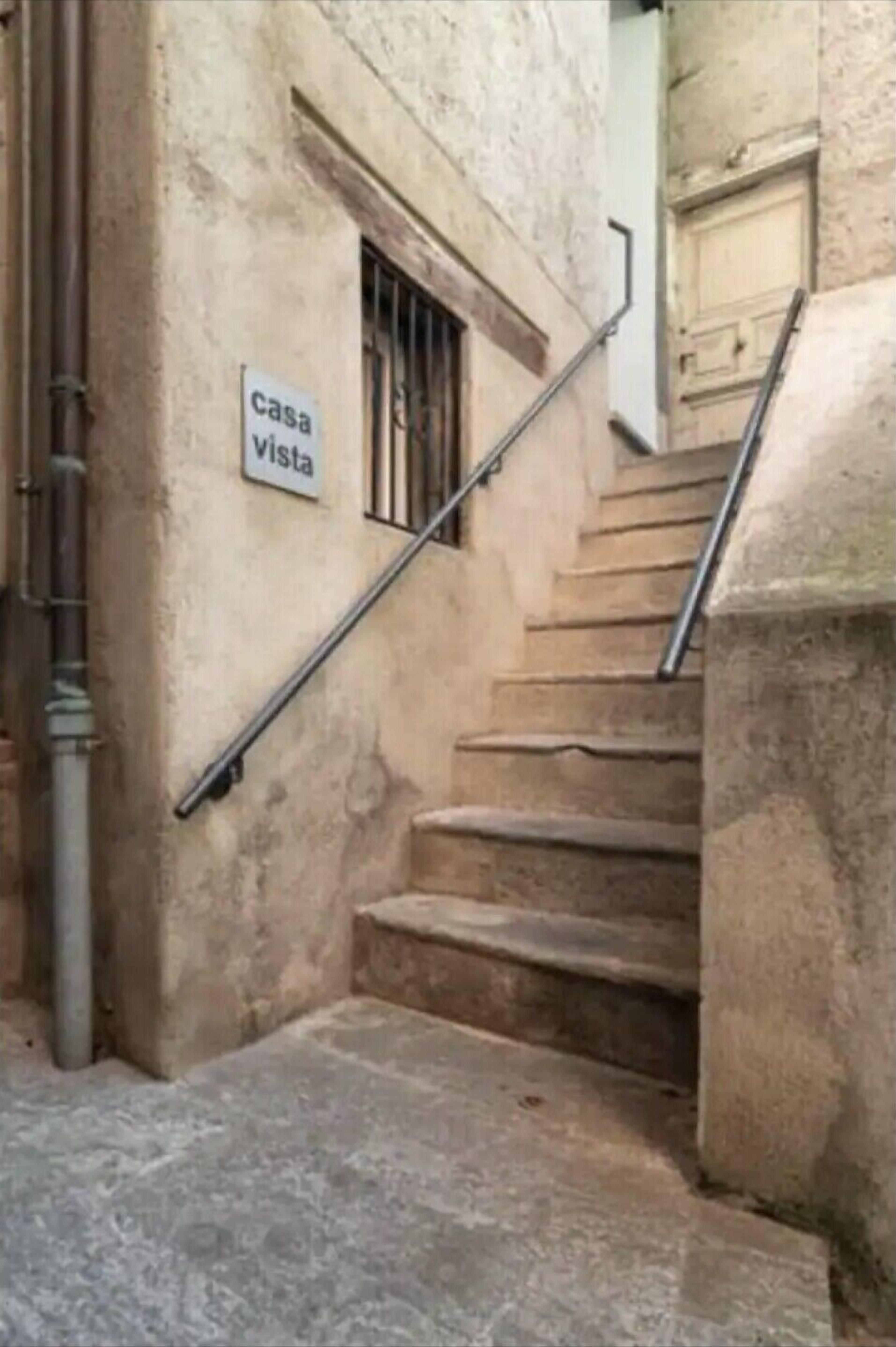 Eine Treppe führt zu einem Gebäude, an dem ein Schild mit der Aufschrift "casa vista" hängt.