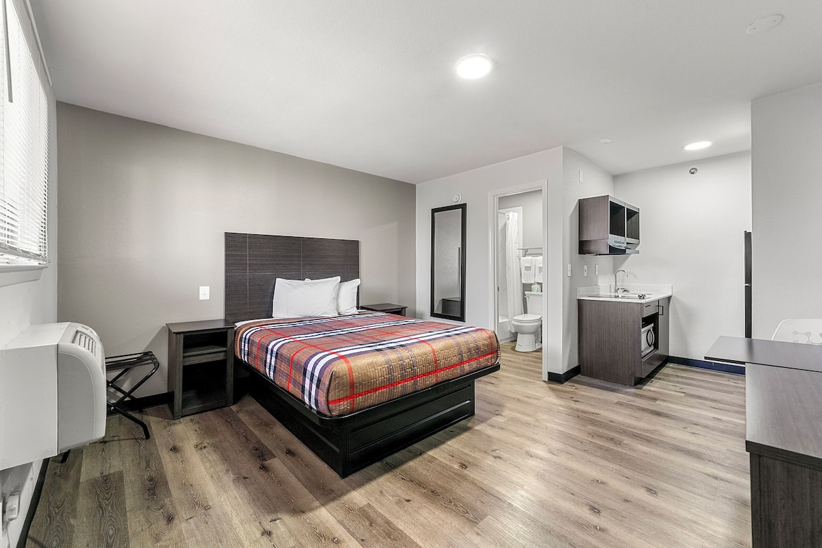 A modern hotel room with a bed, desk, and built-in wardrobe.